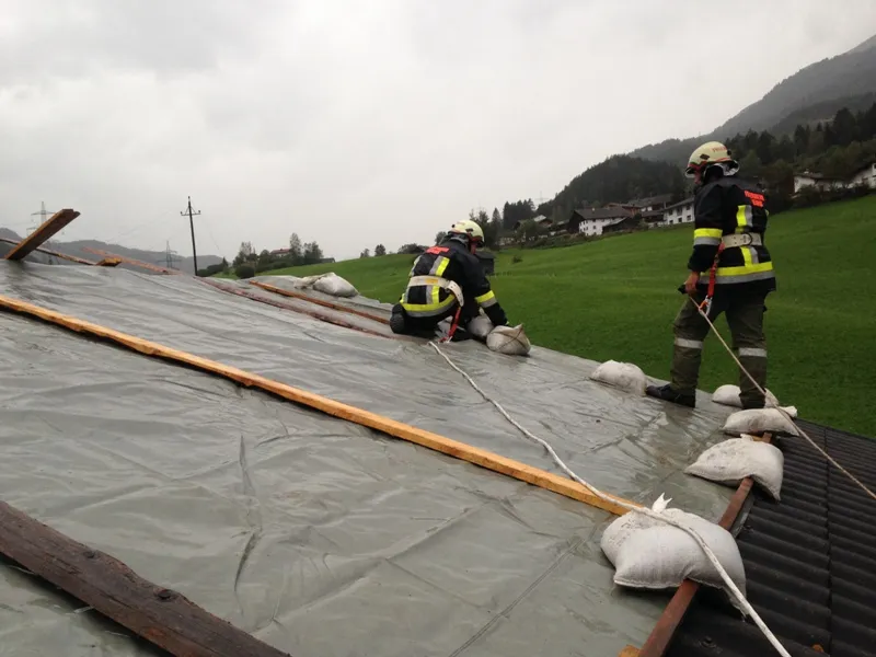 Abgedeckte Dächer und umgestürzte Bäume nach heftigem Sturm